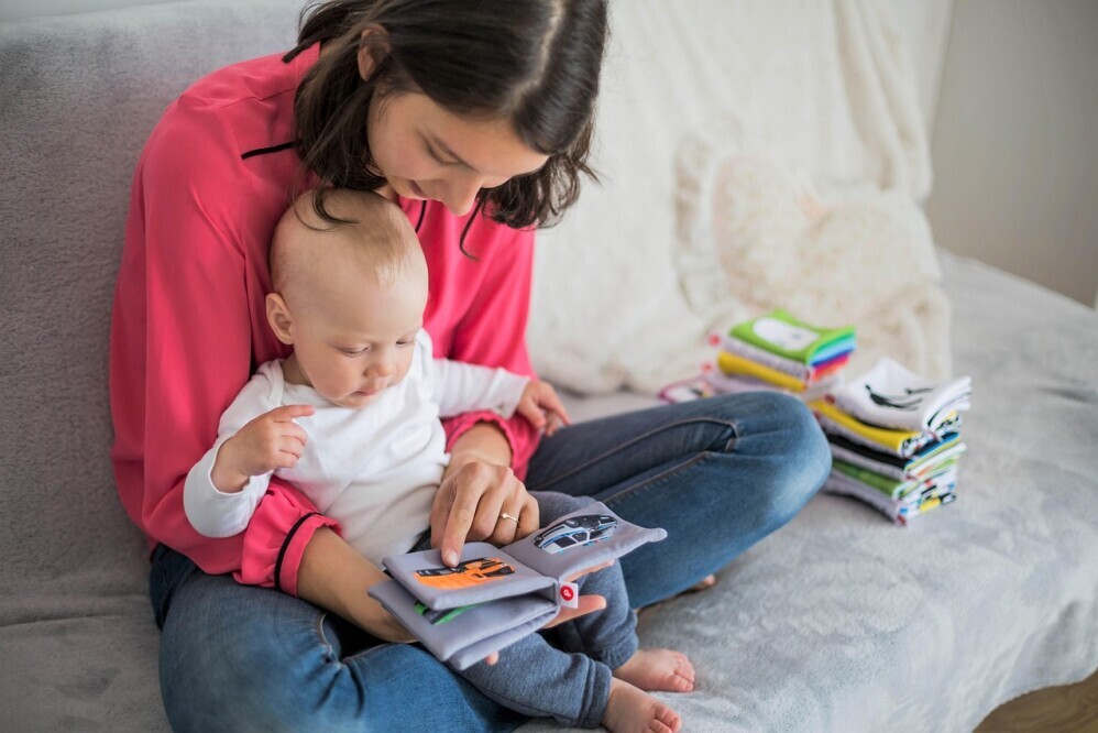 A mother looking at a picture book with her baby